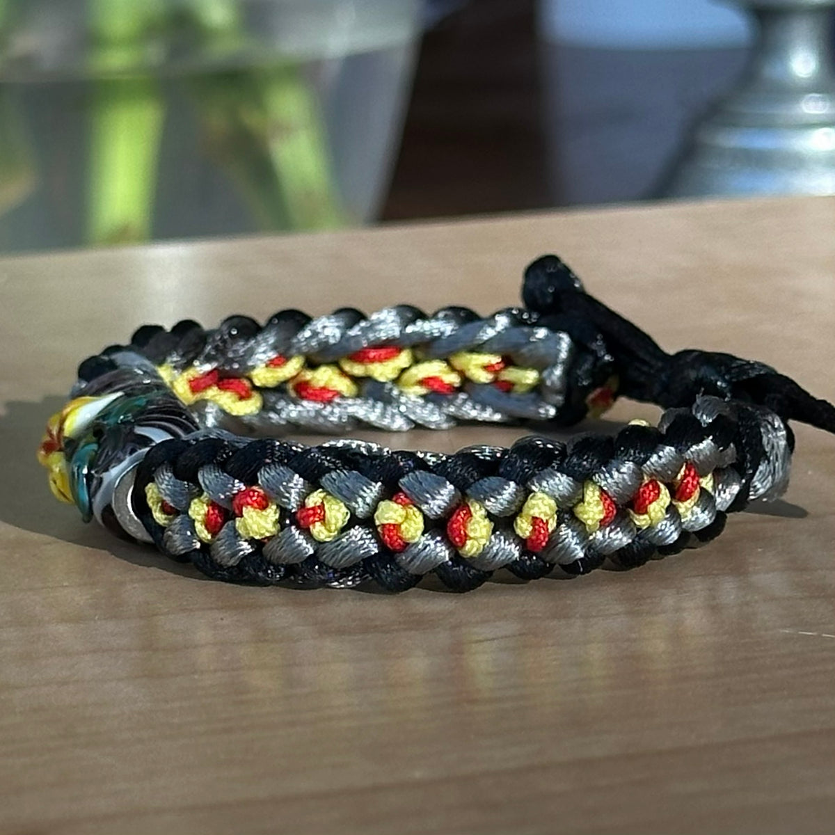 Cinder Marigold | Lampwork Glass Flower Bracelet on Black, Gray, Yellow & Red Braided Cord